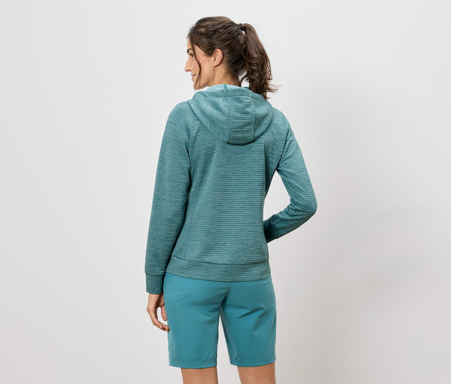 Une femme, vue de dos, porte un sweat à capuche et un short turquoise.