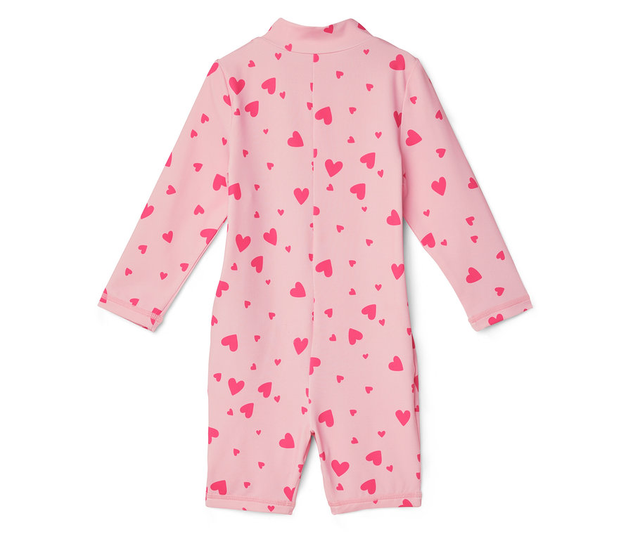 Un maillot de bain rose clair à manches longues et à motifs de cœurs rouges est posé sur un fond blanc.