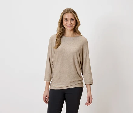 Femme portant un haut beige et un pantalon noir.