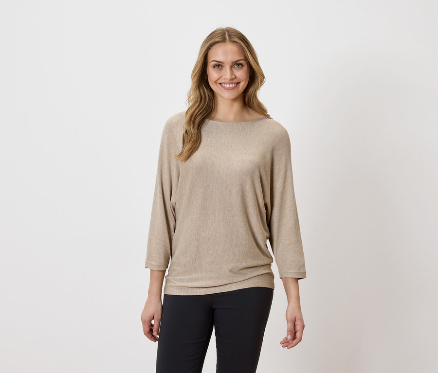 Femme portant un haut beige et un pantalon noir.