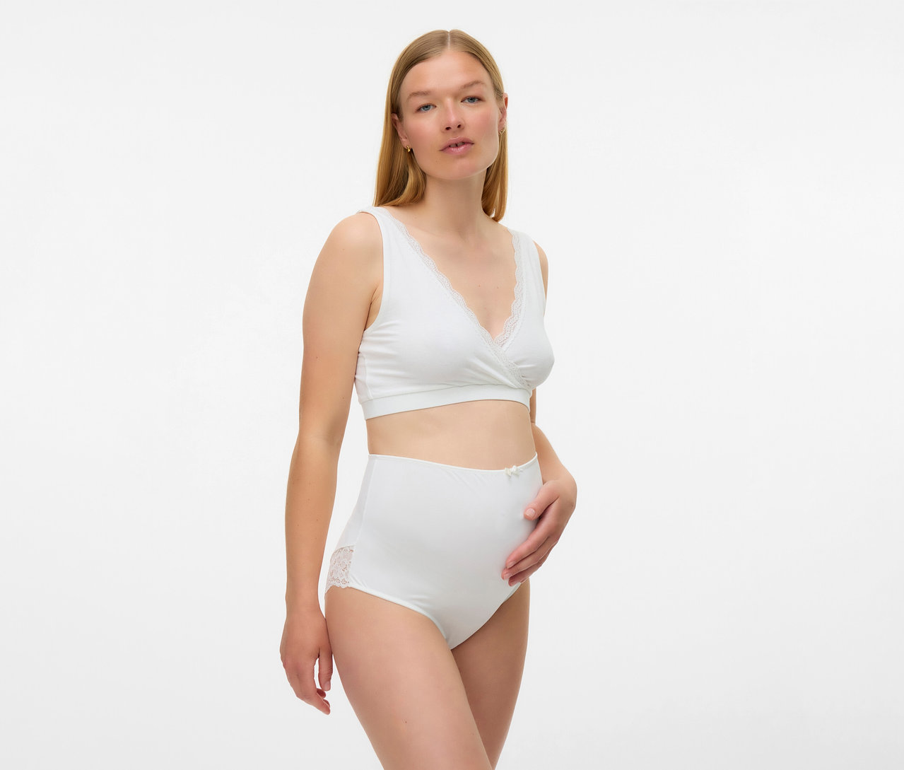 Une femme porte un lot de 2 soutiens-gorge de grossesse et d’allaitement MAMALICIOUS «
MLHELENA
» blancs et une culotte assortie avec de la dentelle.