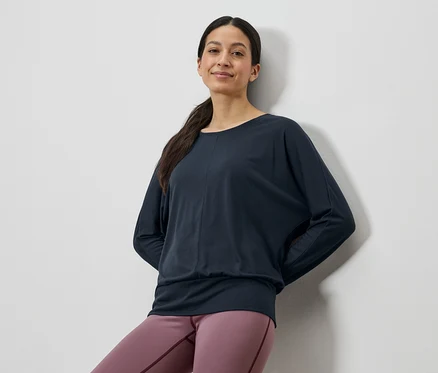 Une femme porte un haut à manches longues bleu marine et un legging rose.