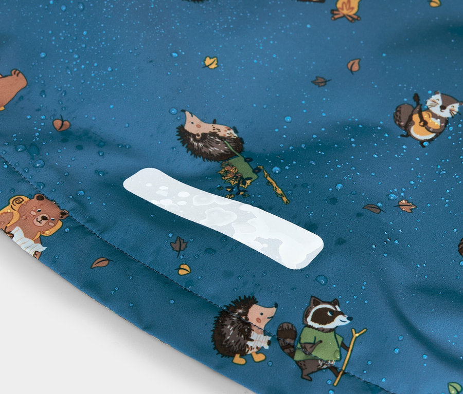 Gros plan d'un tissu bleu avec des motifs de hérissons, d'ours et de ratons laveurs, des gouttes d'eau et une bande réfléchissante blanche.