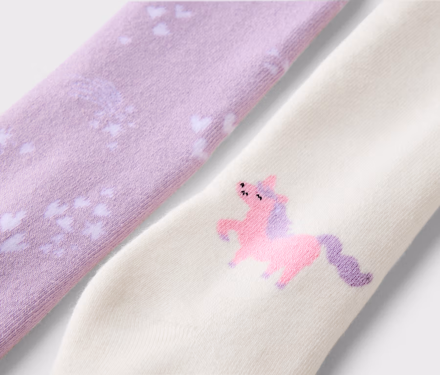 Gros plan de deux chaussettes, une lavande avec des cœurs blancs, l'autre crème avec une licorne rose.