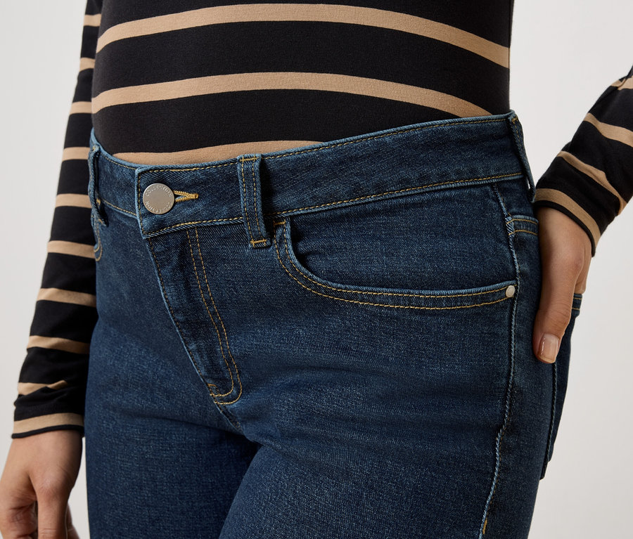 Gros plan d'une femme portant un jean bleu foncé et un haut rayé.