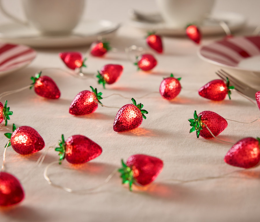 Guirlande lumineuse fraise sur une table avec de la vaisselle.