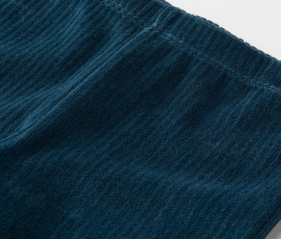 Gros plan d'un pantalon en velours côtelé bleu marine avec une taille élastique.