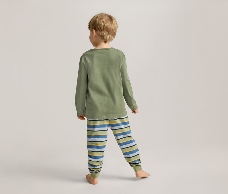 Un enfant blond, vu de dos, porte un t-shirt vert à manches longues et un pantalon rayé.