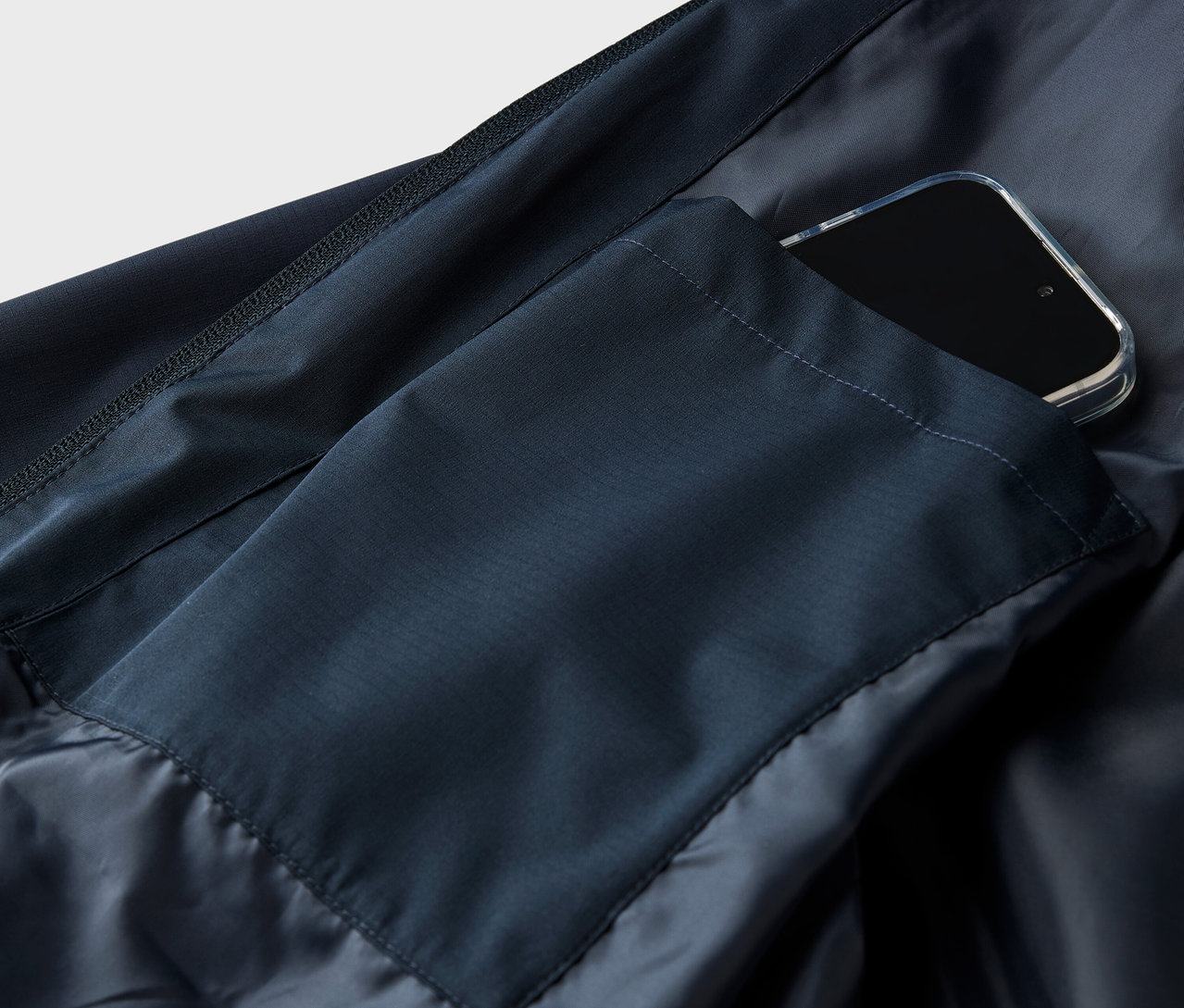 Gros plan d'une veste bleu marine avec un smartphone dans la poche.