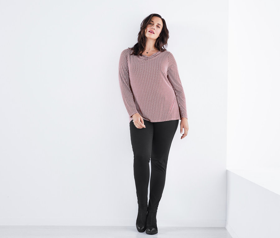 Femme posant en T-shirt à col bénitier, jegging et bottines en cuir.