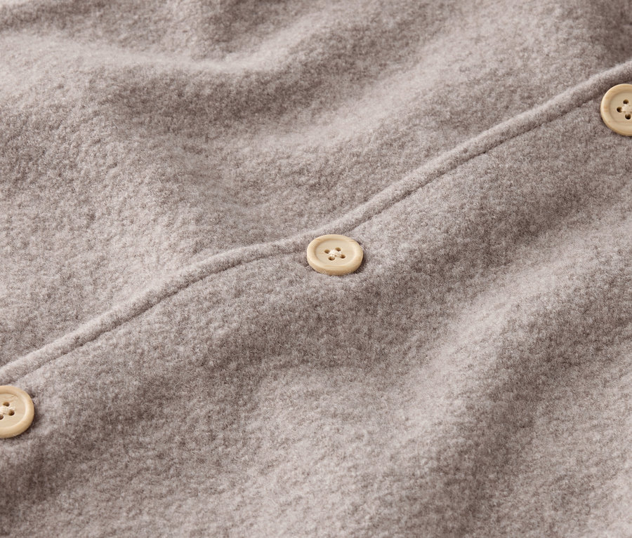 Gros plan d'un tissu de laine gris avec trois boutons beiges.