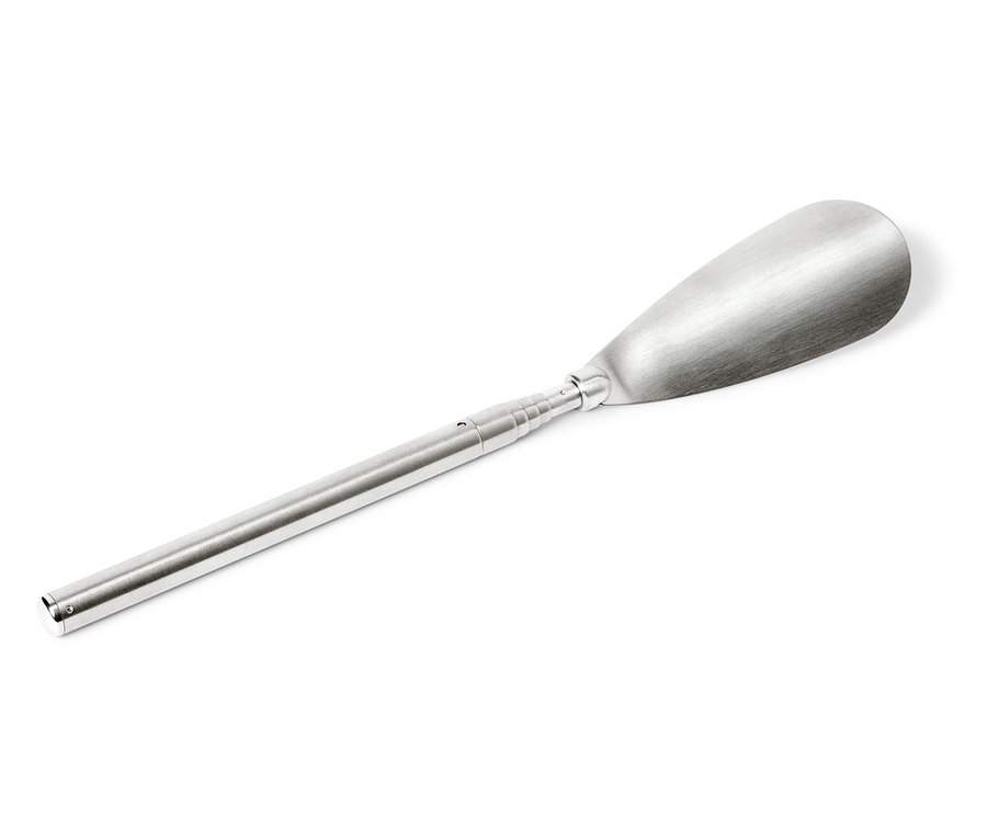 Un chausse-pied argenté est disposé en diagonale sur un fond blanc.