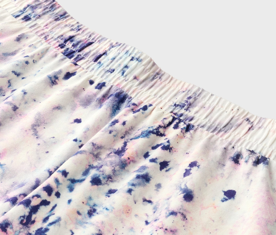 Gros plan d'un short avec une taille élastique et un motif tie-dye violet, bleu et rose.