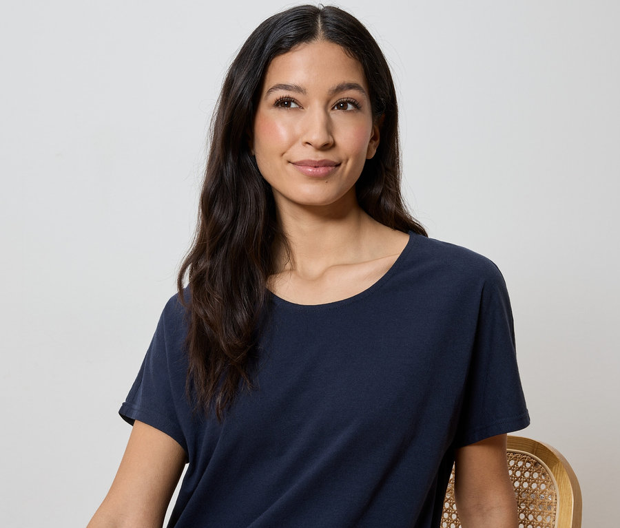 Femme aux longs cheveux foncés portant un t-shirt bleu marine.
