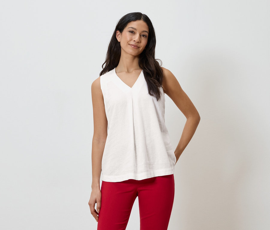 Une femme porte un haut sans manches blanc et un pantalon rouge.