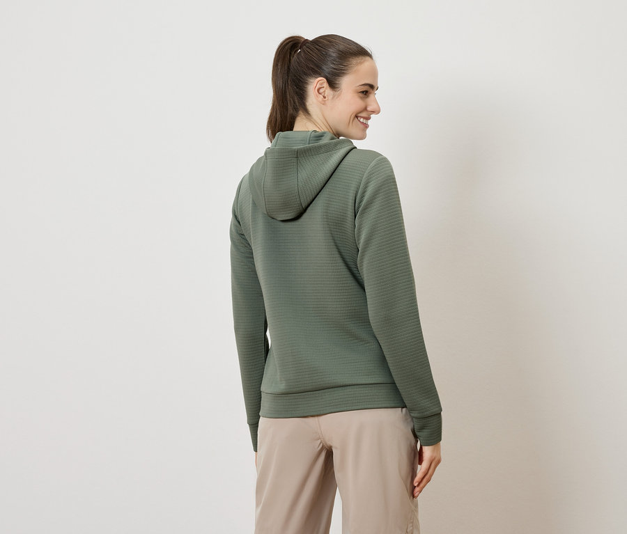Femme de dos portant un sweat à capuche vert olive et un short beige.