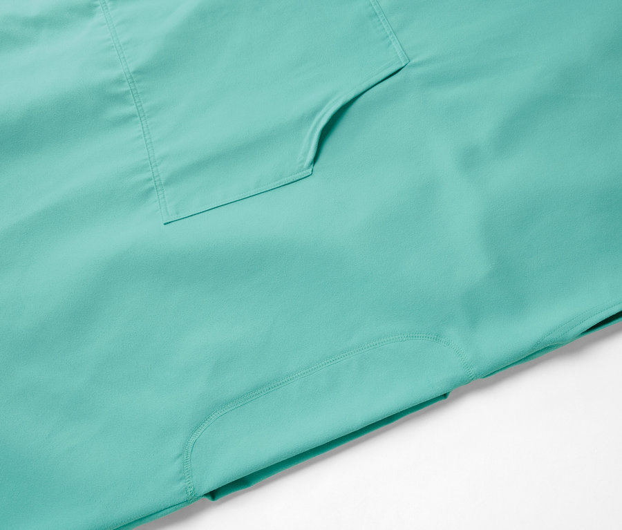 Gros plan d'un haut turquoise avec une poche plaquée et une couture latérale suggérée.
