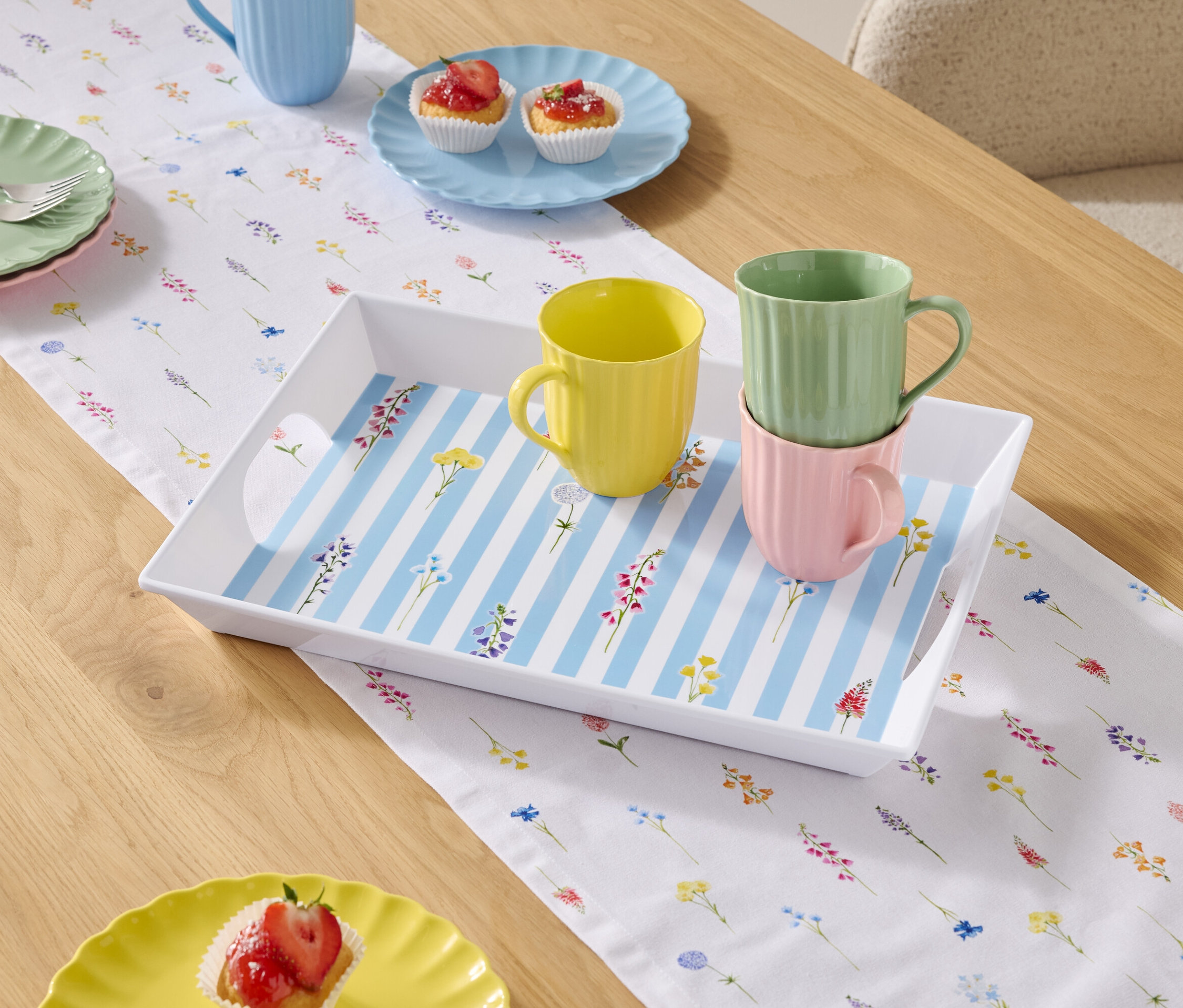 Table à manger avec vaisselle et tasses sur une nappe à fleurs.