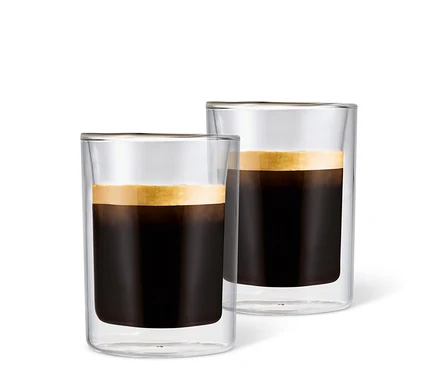 Deux verres à café crème remplis de café avec de la mousse sur fond blanc.