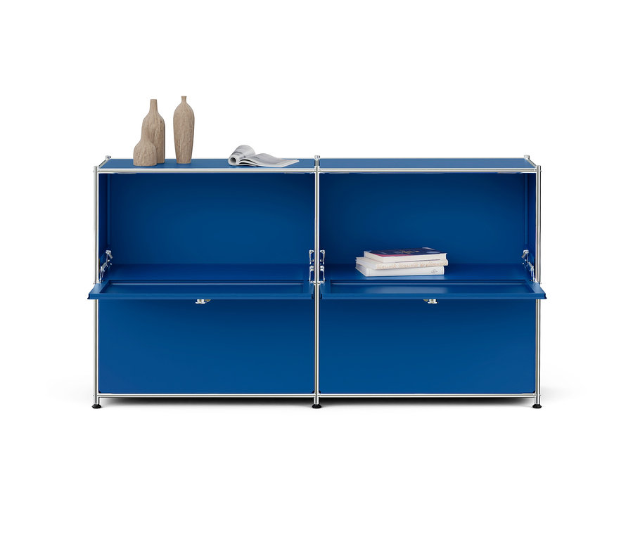 Armoire modulaire bleue avec cadre chromé, deux portes abattantes ouvertes et des décorations. À gauche, trois vases et un magazine, à droite, trois livres.