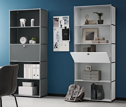 Pièce avec bureau, chaise et deux étagères hautes en métal avec un compartiment à abattant amovible. Un caisson à roulettes en métal est à gauche et un ordinateur portable sur la table.