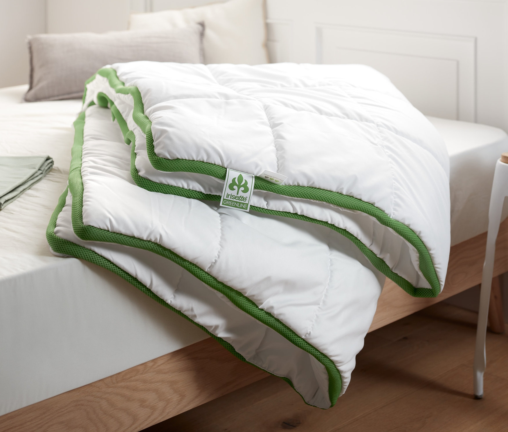 Sur un lit, une couette blanche irisette® greenline à bande thermorégulatrice.