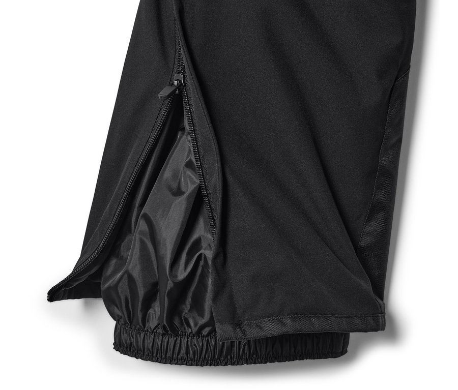 Gros plan sur un pantalon de ski high-tech noir avec fermeture éclair ouverte sur la jambe.