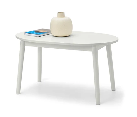Un vase et un livre sont posés sur une table basse blanche.