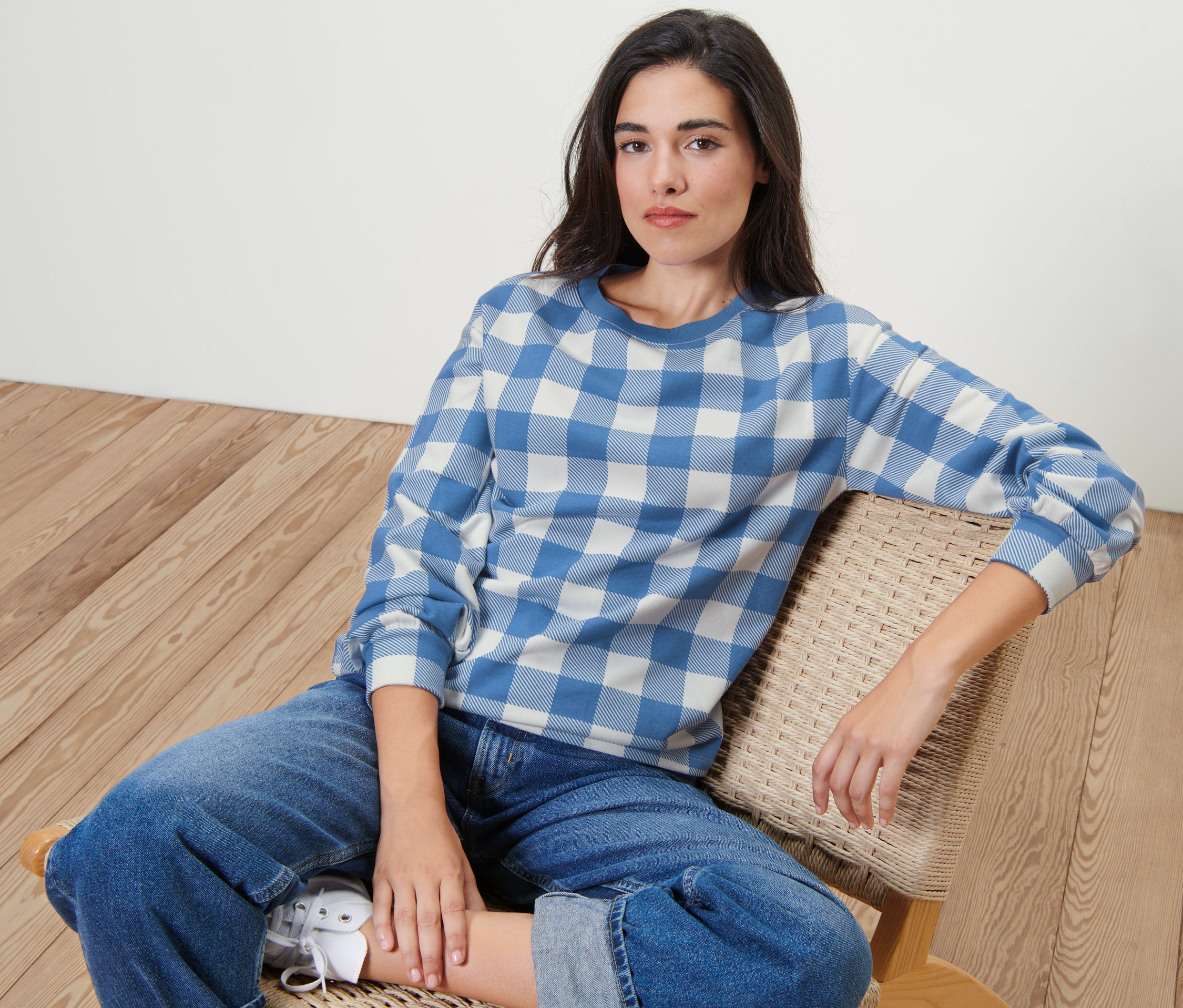 Femme assise sur une chaise portant un sweat-shirt à carreaux.