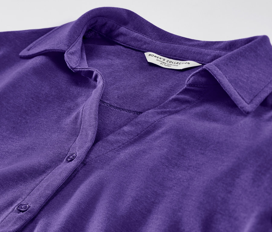 Gros plan sur une blouse violette avec patte de boutonnage.