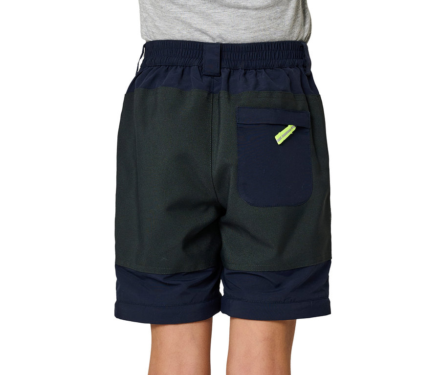 Enfant de dos portant un pantalon zip-off JAKO-O marine, porté en short. Le short est gris foncé et bleu marine, avec une poche arrière et un détail jaune fluo.