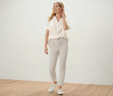 Femme posant dans un chemisier clair et un pantalon rayé en twill stretch.
