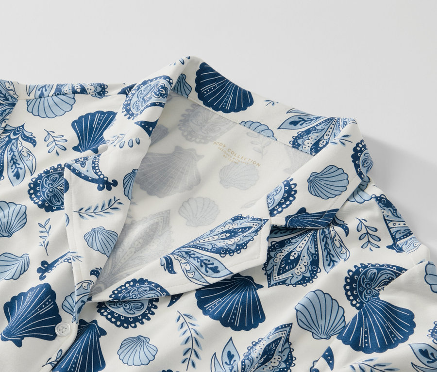 Gros plan sur un pyjama avec un imprimé bleu de coquillages et de motifs cachemire sur un fond blanc.