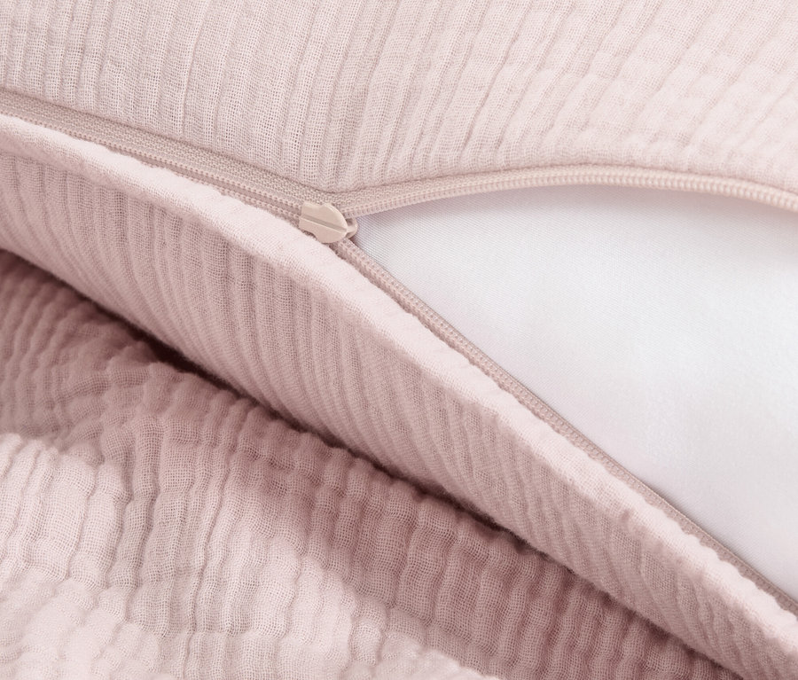 Gros plan d'une parure de lit en mousseline rose avec fermeture éclair.