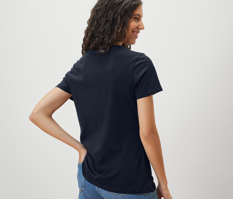 Femme portant un t-shirt basique bleu foncé et un jean.
