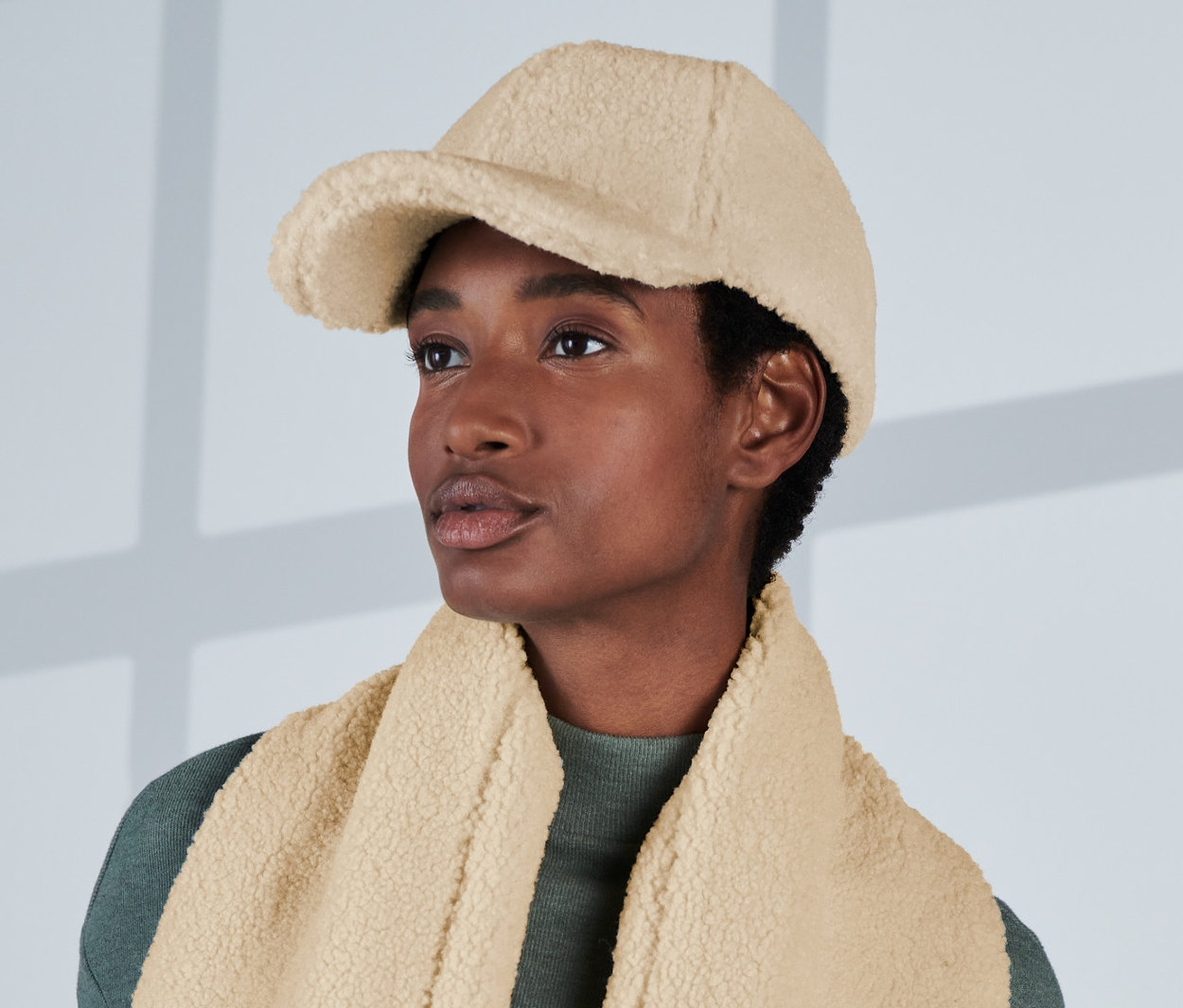 Femme portant une casquette en peluche blanc crème et une écharpe.