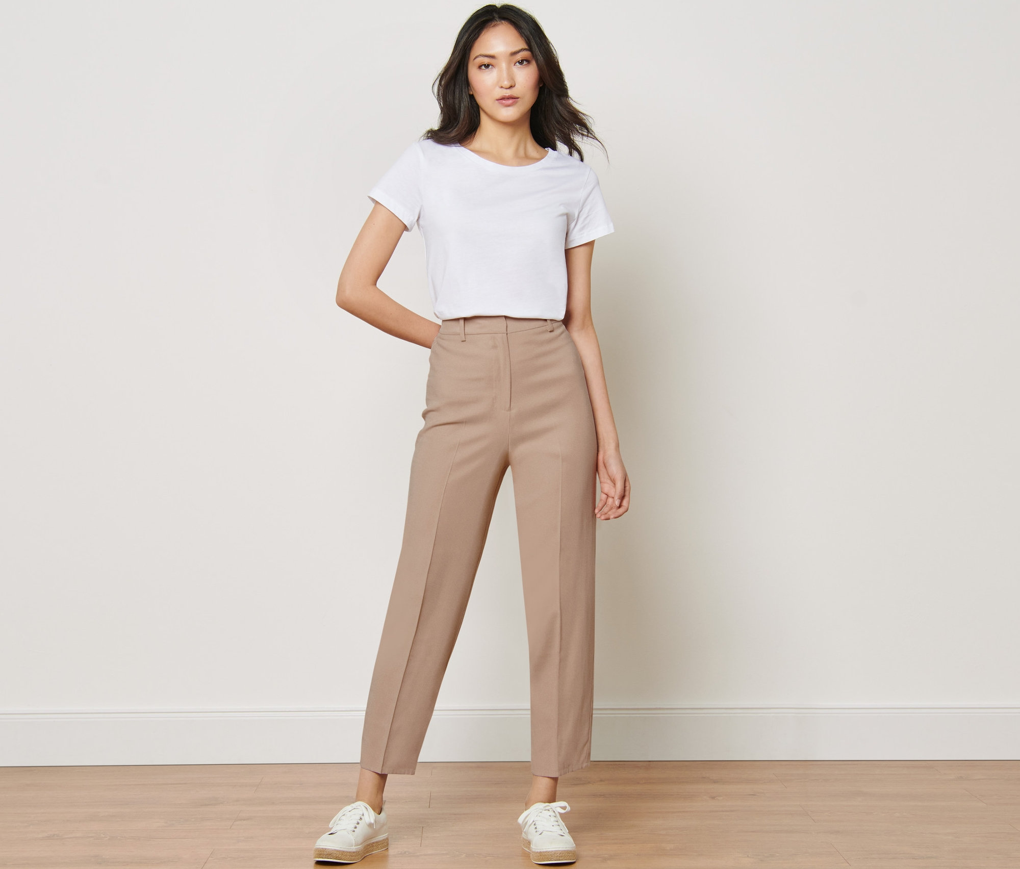 Femme posant en t-shirt blanc et pantalon tissé.