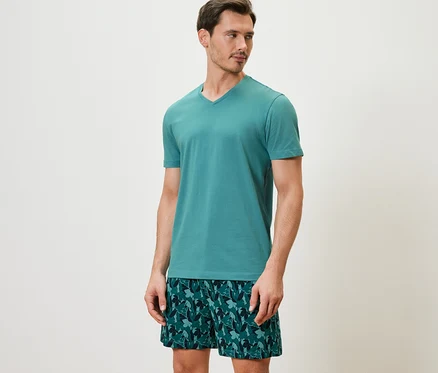 Un homme porte un ensemble pyjama shorty avec un haut à manches courtes et un short imprimé.