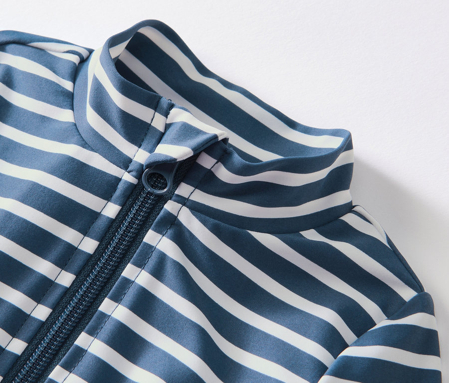 Gros plan sur une combinaison rayée bleu et blanc pour bébé avec protection UV 80 et fermeture éclair.