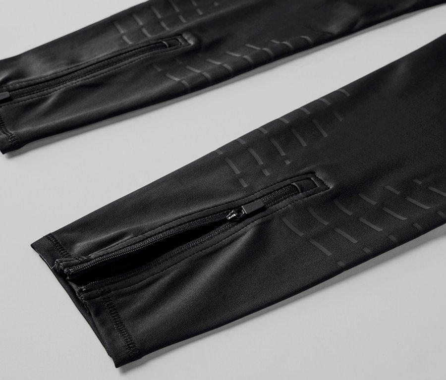 Vue détaillée d'un legging de sport noir avec fermetures éclair aux chevilles.