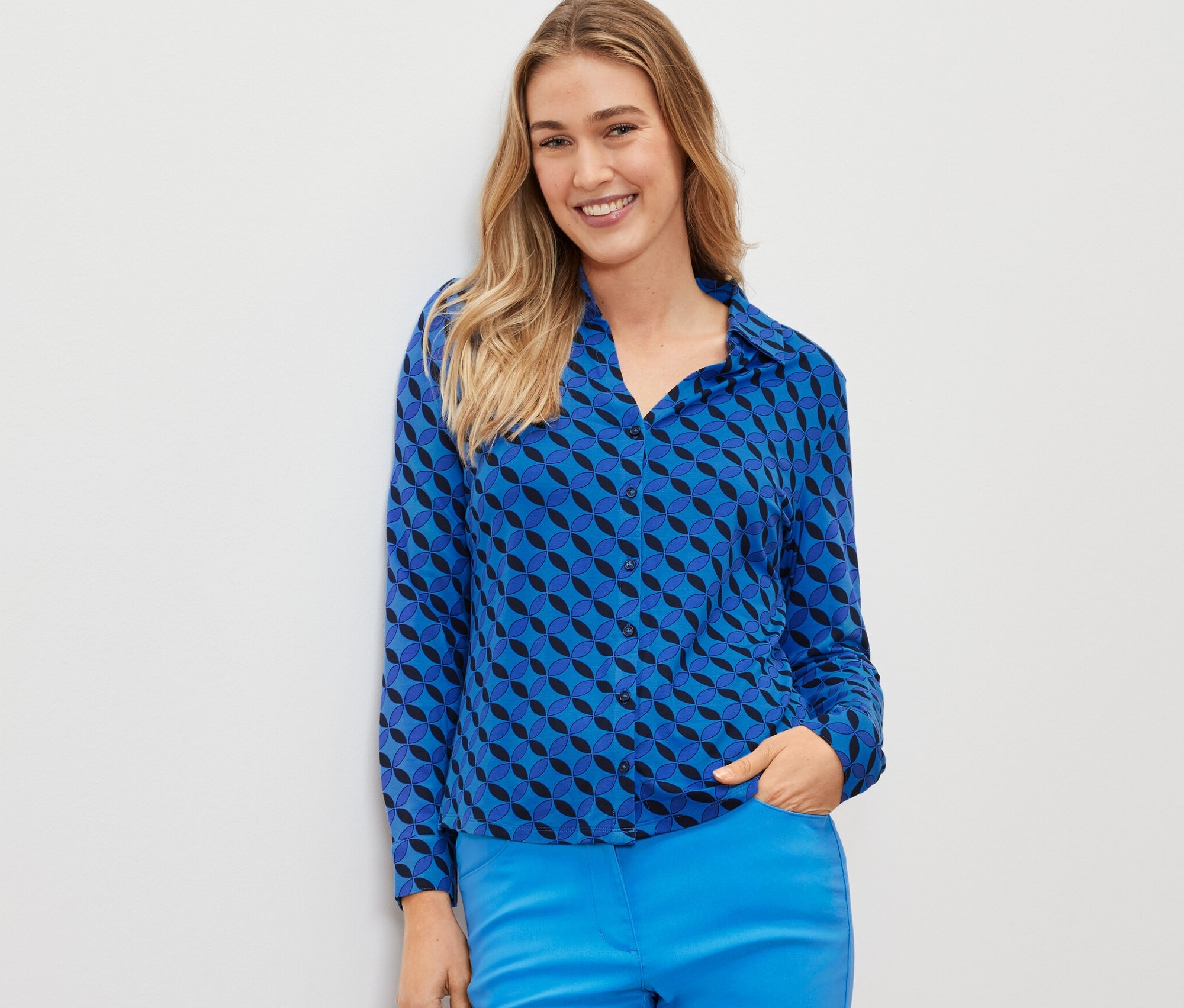 Une femme porte une blouse bleue avec patte de boutonnage.