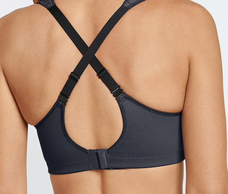 Vue arrière d'une femme portant un soutien-gorge de sport gris avec des bretelles noires.