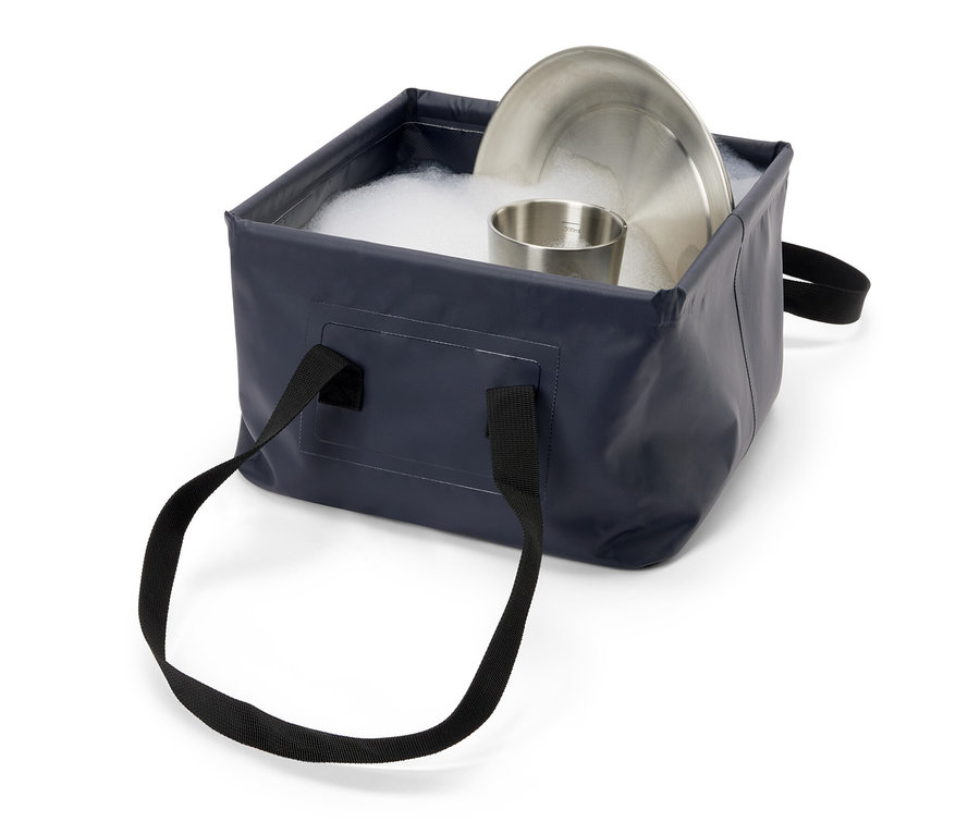Assiette et tasse en acier inoxydable dans un évier pliable bleu avec de l'eau savonneuse.