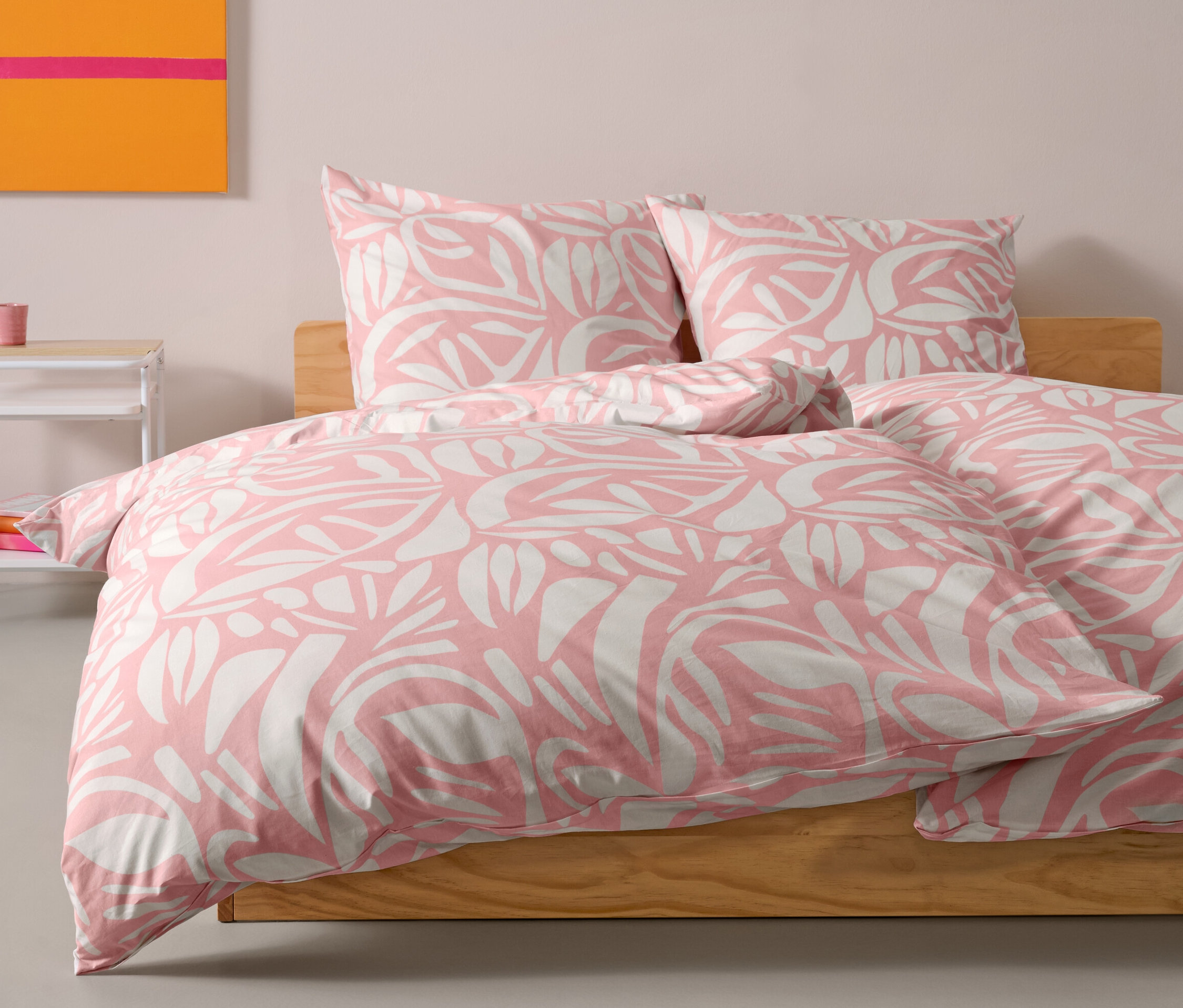 Une parure de lit en renforcé rose de taille standard est posée sur un lit. Deux oreillers sont placés derrière la couette.