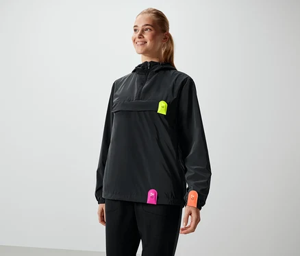 Femme souriant dans une veste noire avec des détails néon.