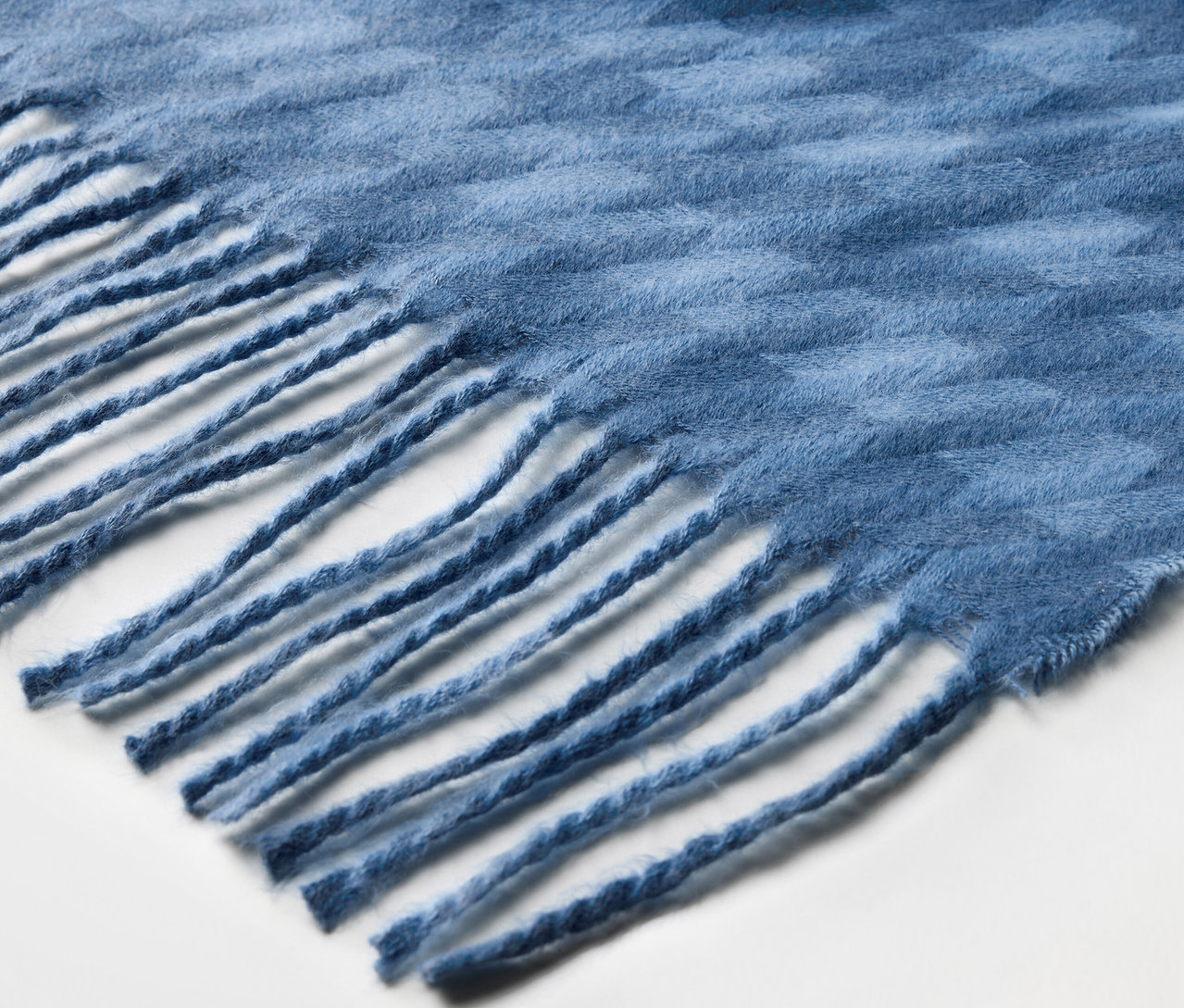 Gros plan d'une écharpe bleue à franges.