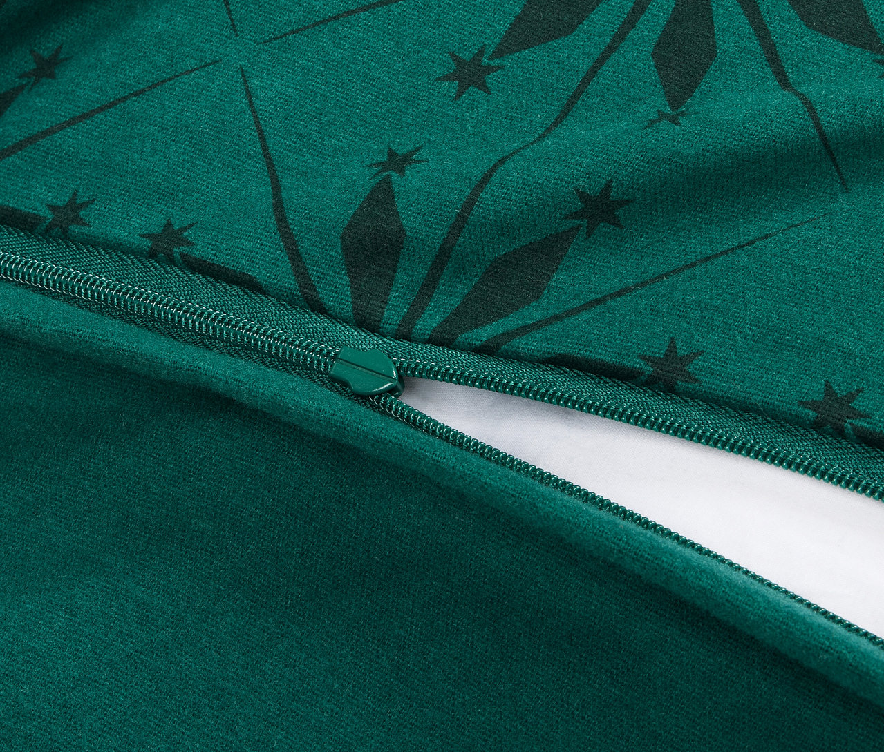 Vue détaillée d'une fermeture éclair ouverte sur une housse de couette verte avec un motif géométrique vert foncé.