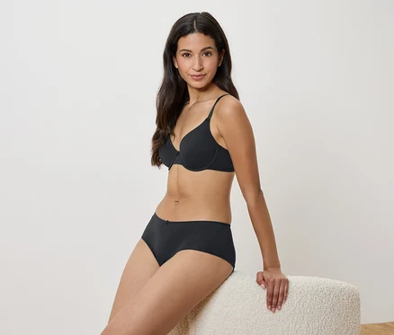 Femme assise sur un tabouret en soutien-gorge et culotte noirs.