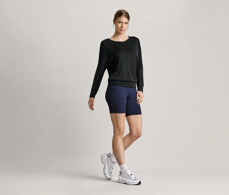 Femme portant un t-shirt de sport et de yoga noir et un collant de sport court.