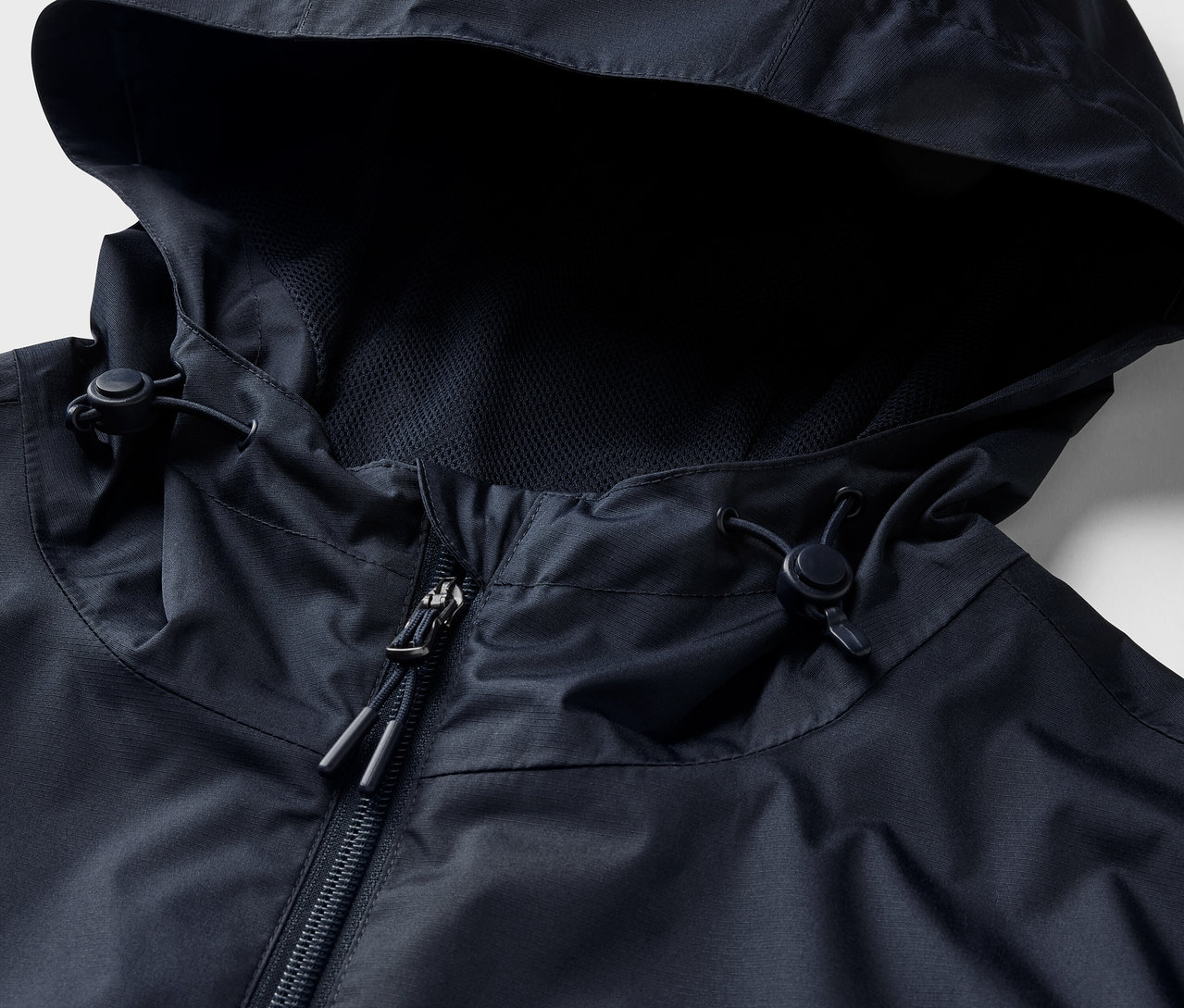 Gros plan sur une veste de pluie bleu marine avec capuche et fermeture éclair.